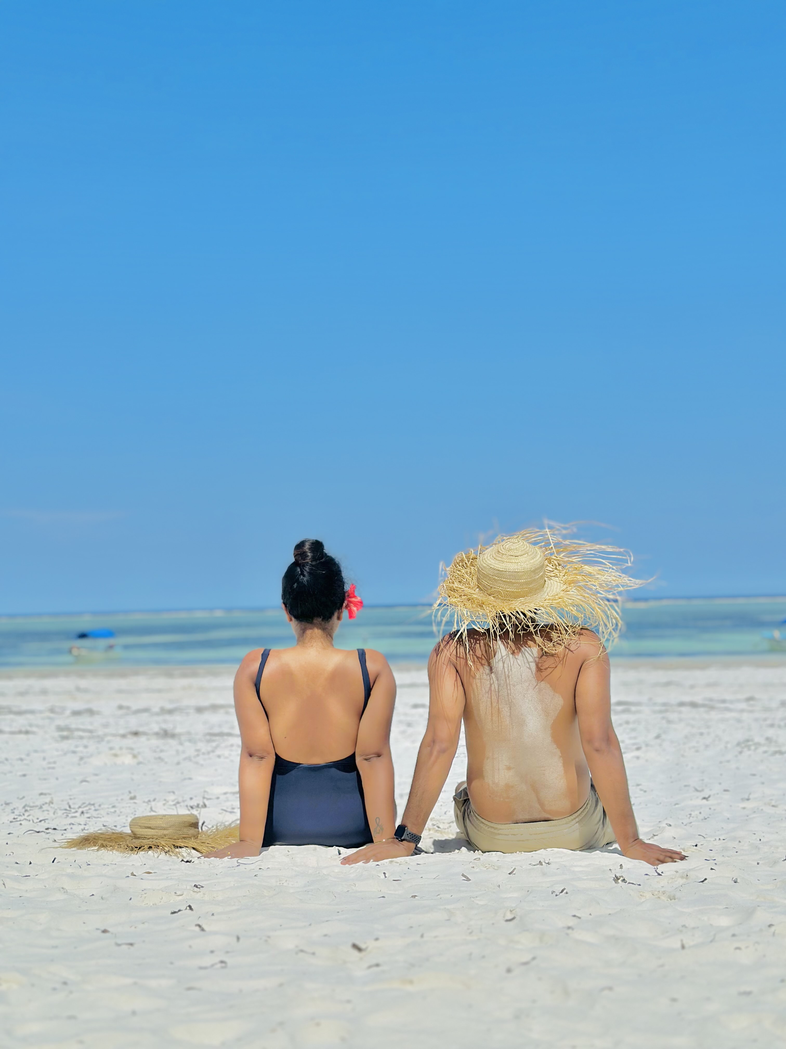 Two travellers with backpacks overlooking a turquoise coastline